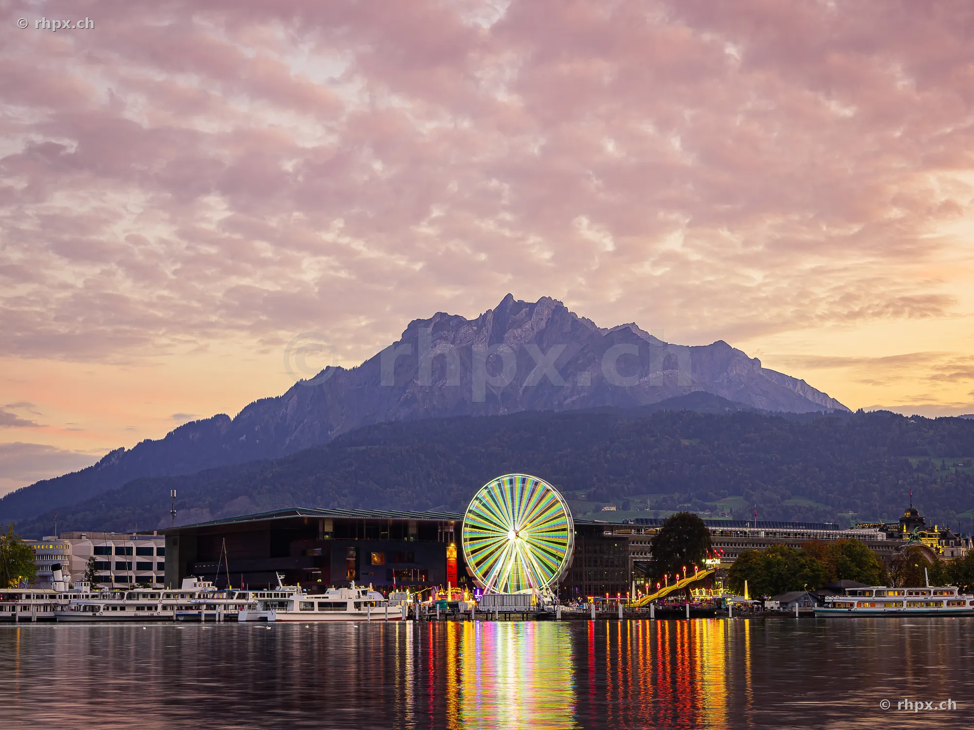 Ferris wheel of the autumn fair in front of Mount Pilatus at dusk