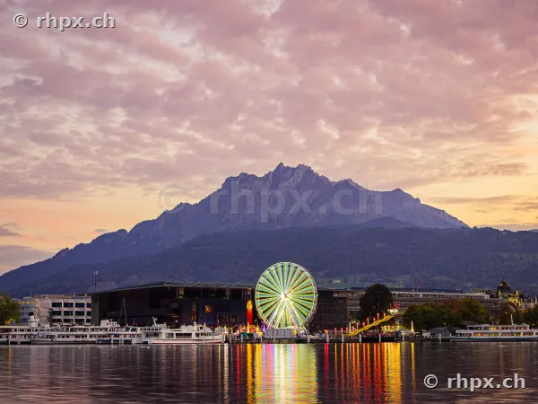 Ferris wheel of the autumn fair in front of Mount Pilatus at dusk