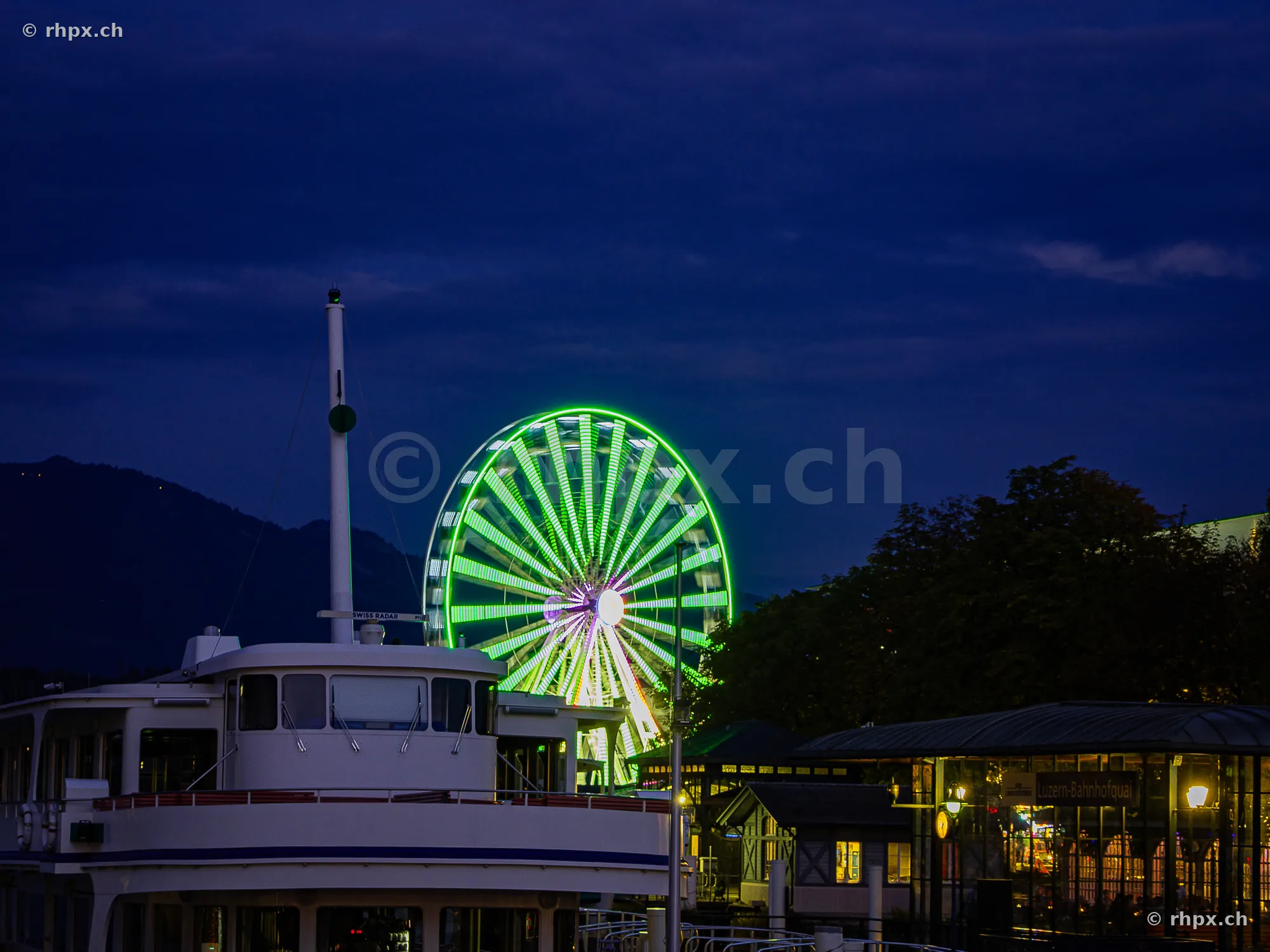 Riesenrad der Lozärner Määs am Luzerner Seebecken bei Nacht mit Schiff im Vordergrund