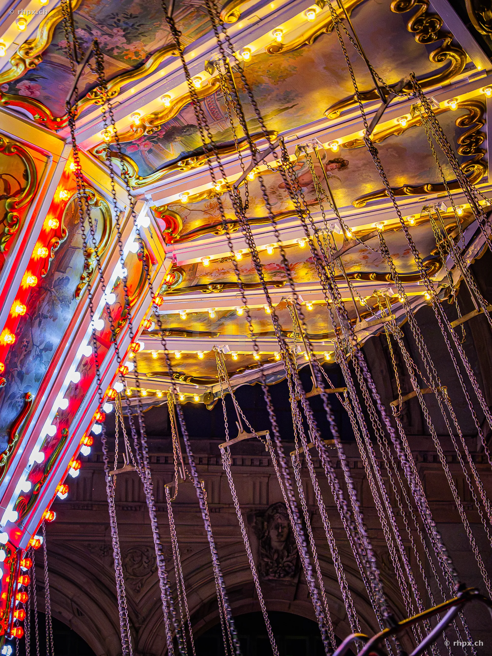 Close-up of chains and ceiling construction of a chain carousel at night at the Lucerne autumn fair.