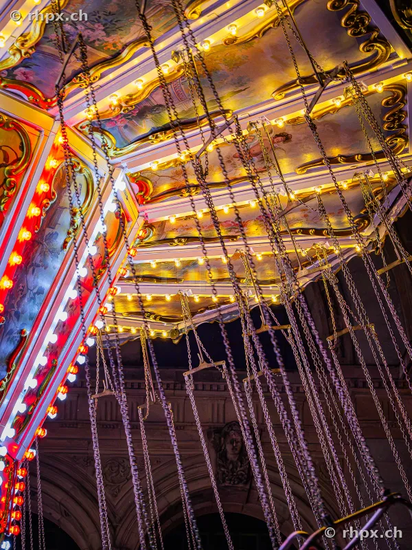 Close-up of chains and ceiling construction of a chain carousel at night at the Lucerne autumn fair.
