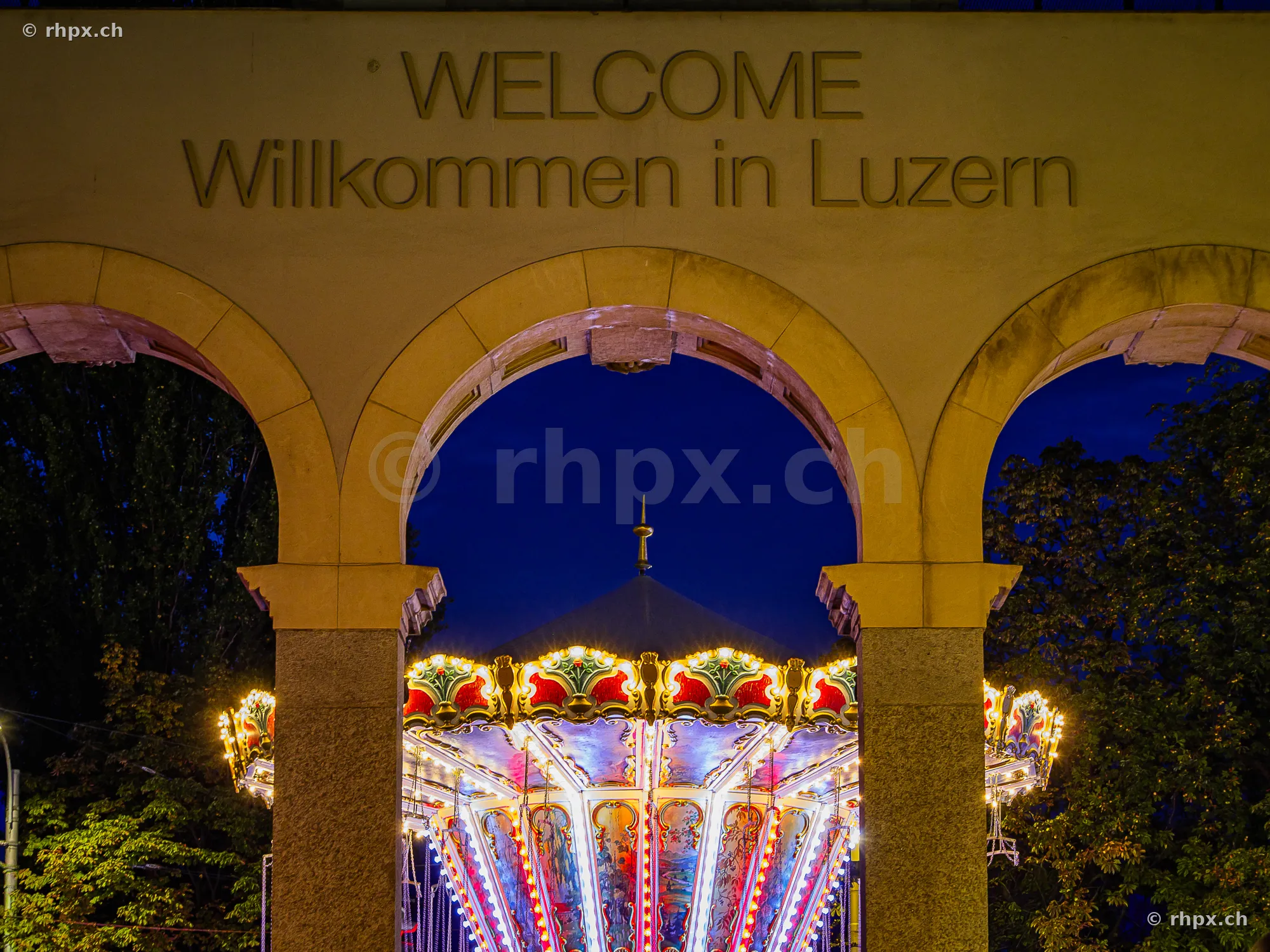 The illuminated carousel of the Lucerne Autumn Fair under the archway