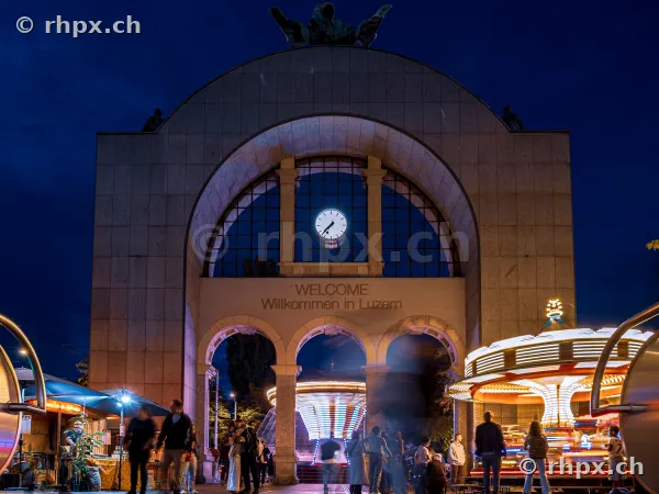 Entrance gate to the Lucerne autumn fair with illuminated carousel at night