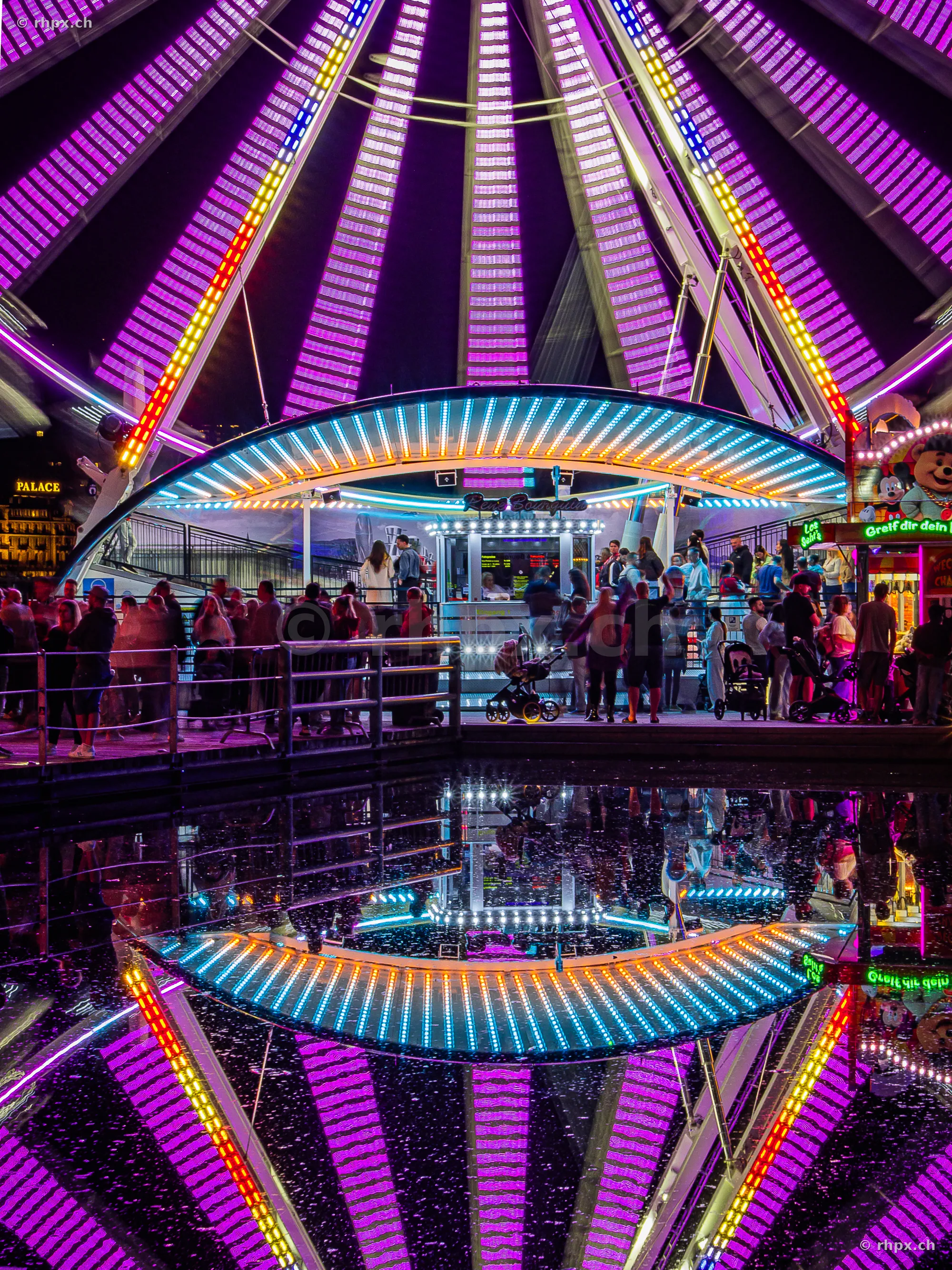 Beleuchtetes Riesenrad bei Nacht mit spiegelnder Fläche an der Luzerner Herbstmesse