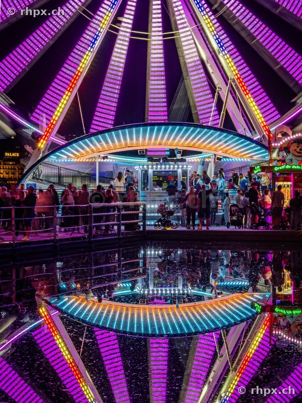 Illuminated Ferris wheel at night with reflection at the Lucerne Autumn Fair