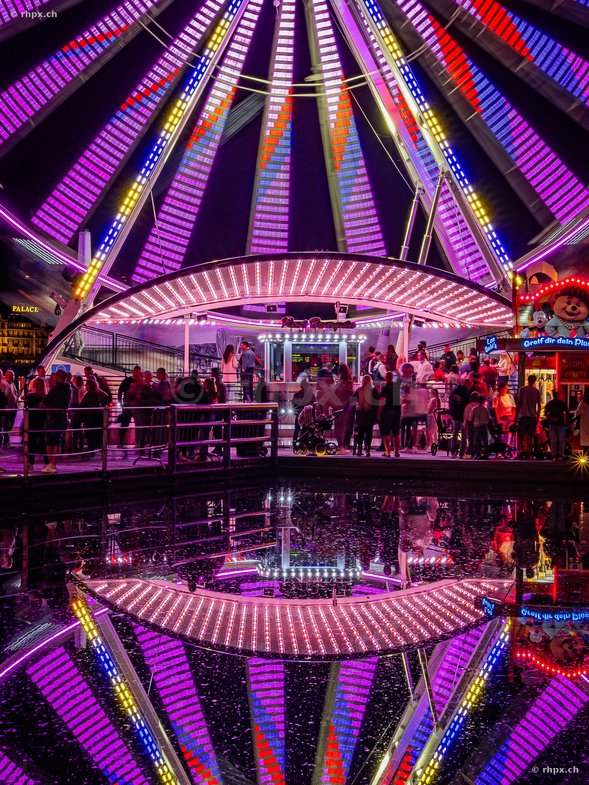 Ferris wheel at the Lucerne Määs at night with light reflection in the water.