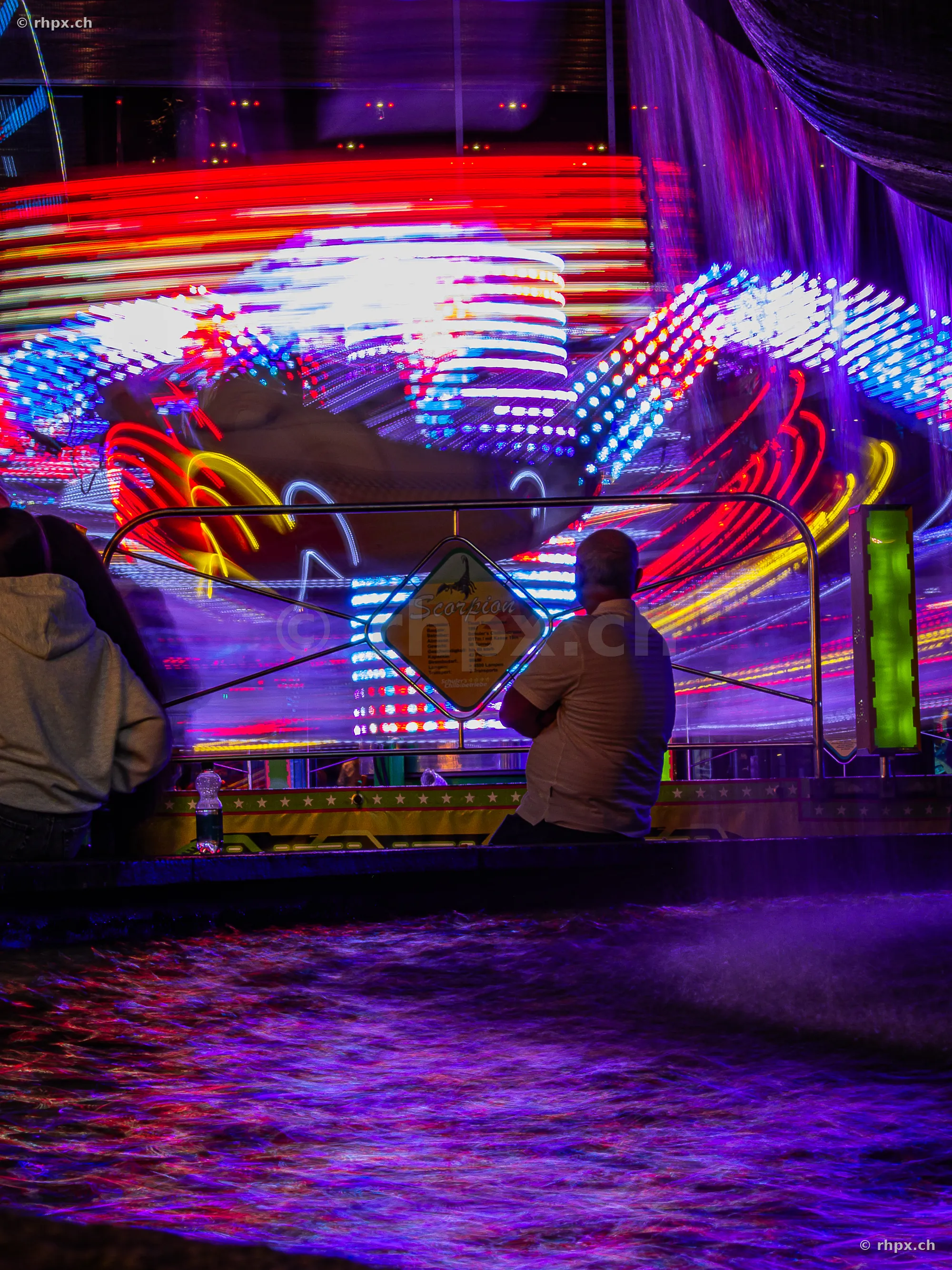 People watching a brightly lit carousel at night at the Lucerne Fair.