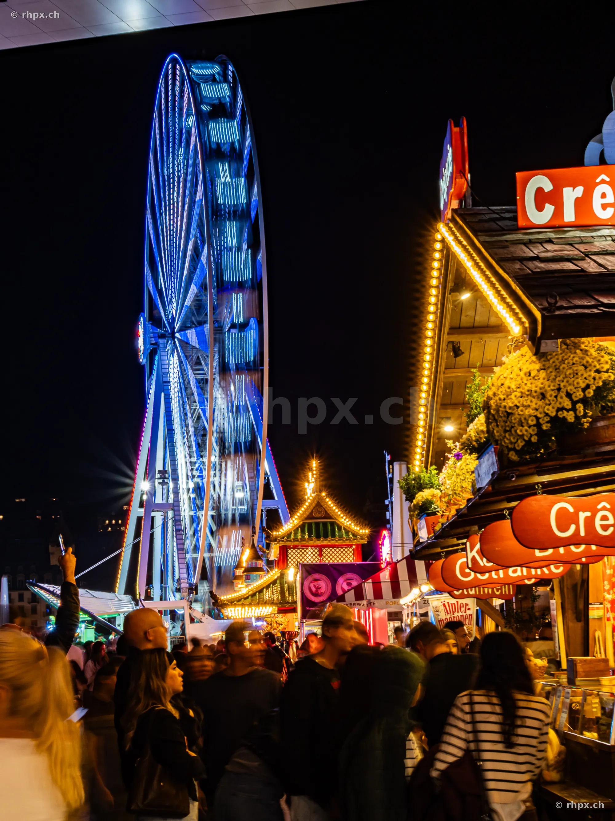 Nächtliche Szene auf der Luzerner Herbstmesse mit beleuchtetem Riesenrad und Verkaufsständen.