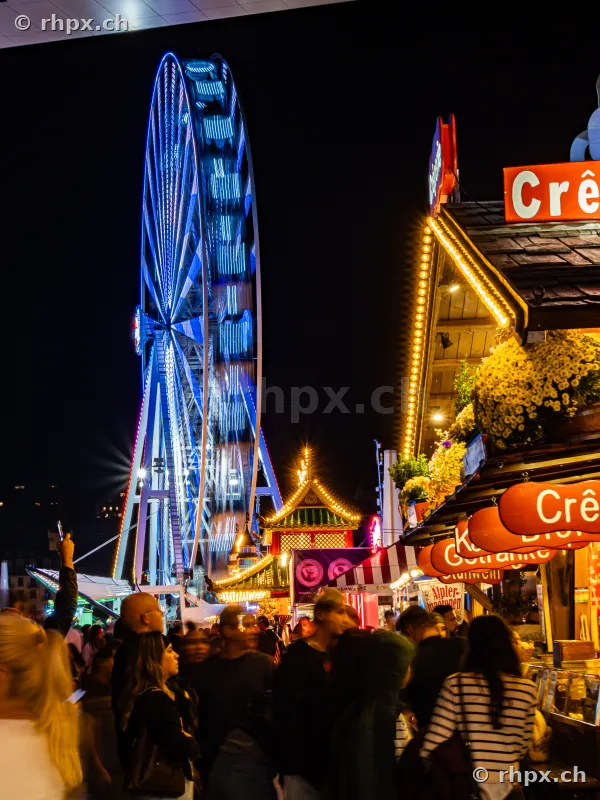 Night scene at the Lucerne autumn fair with an illuminated ferris wheel and market stalls.
