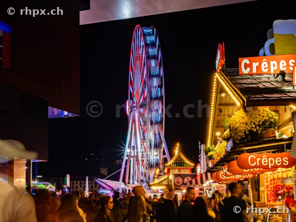 Ferris wheel and illuminated market stalls at the Lucerne Autumn Fair at night