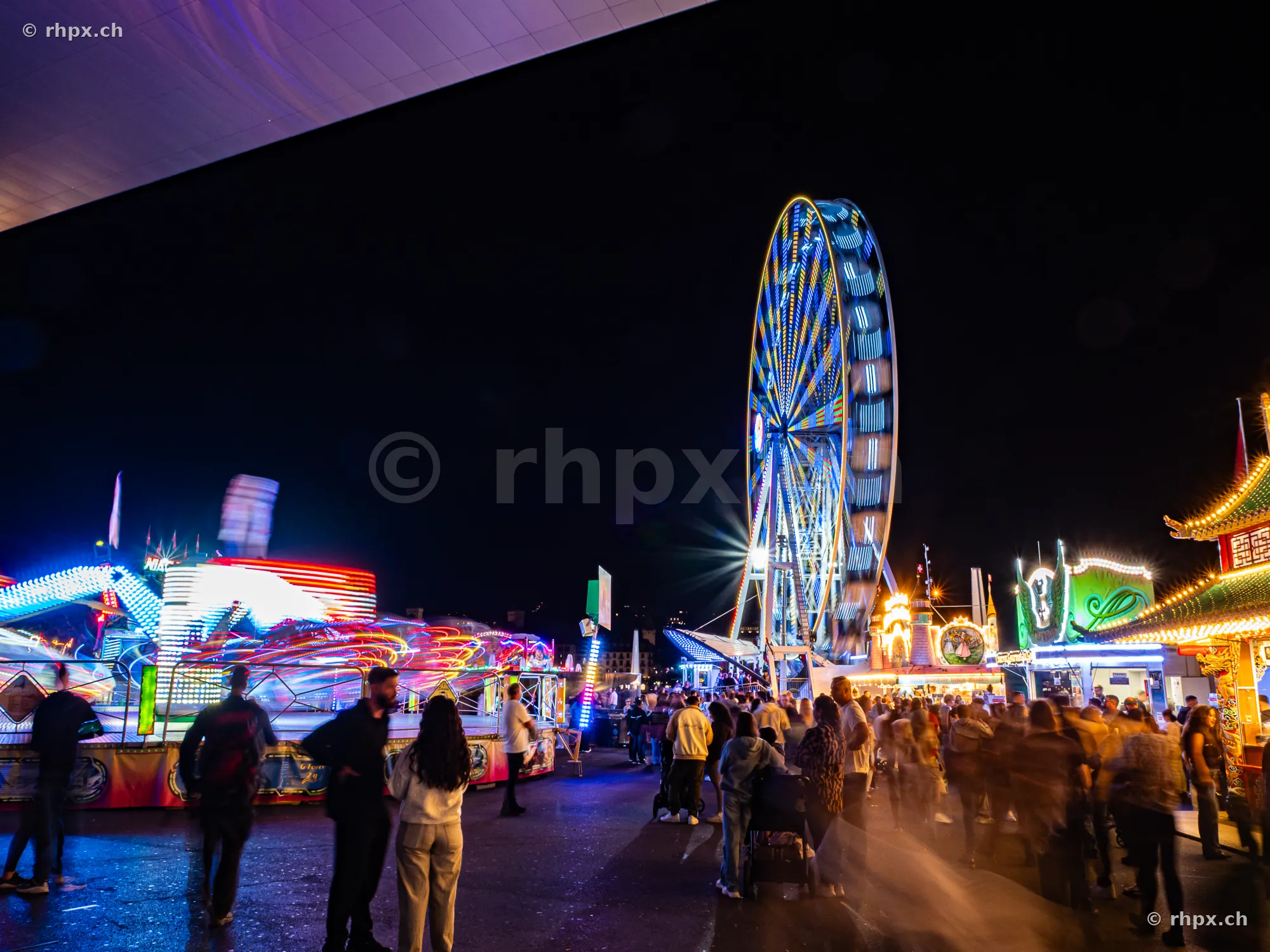 Ferris wheel and amusement rides at night at the Lozärner Määs fairground