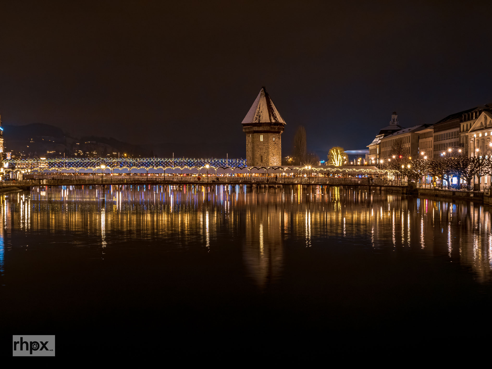 Kapellbrücke und Reuss in Luzern mit warmer Beleuchtung und winterlicher Abendstimmung.