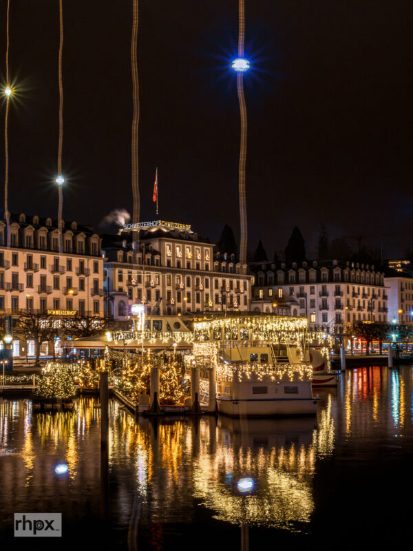 Blick von der Seebrücke in Luzern zur Kapellbrücke und zum Wasserturm mit Weihnachtsbeleuchtung zur blauen Stunde.
